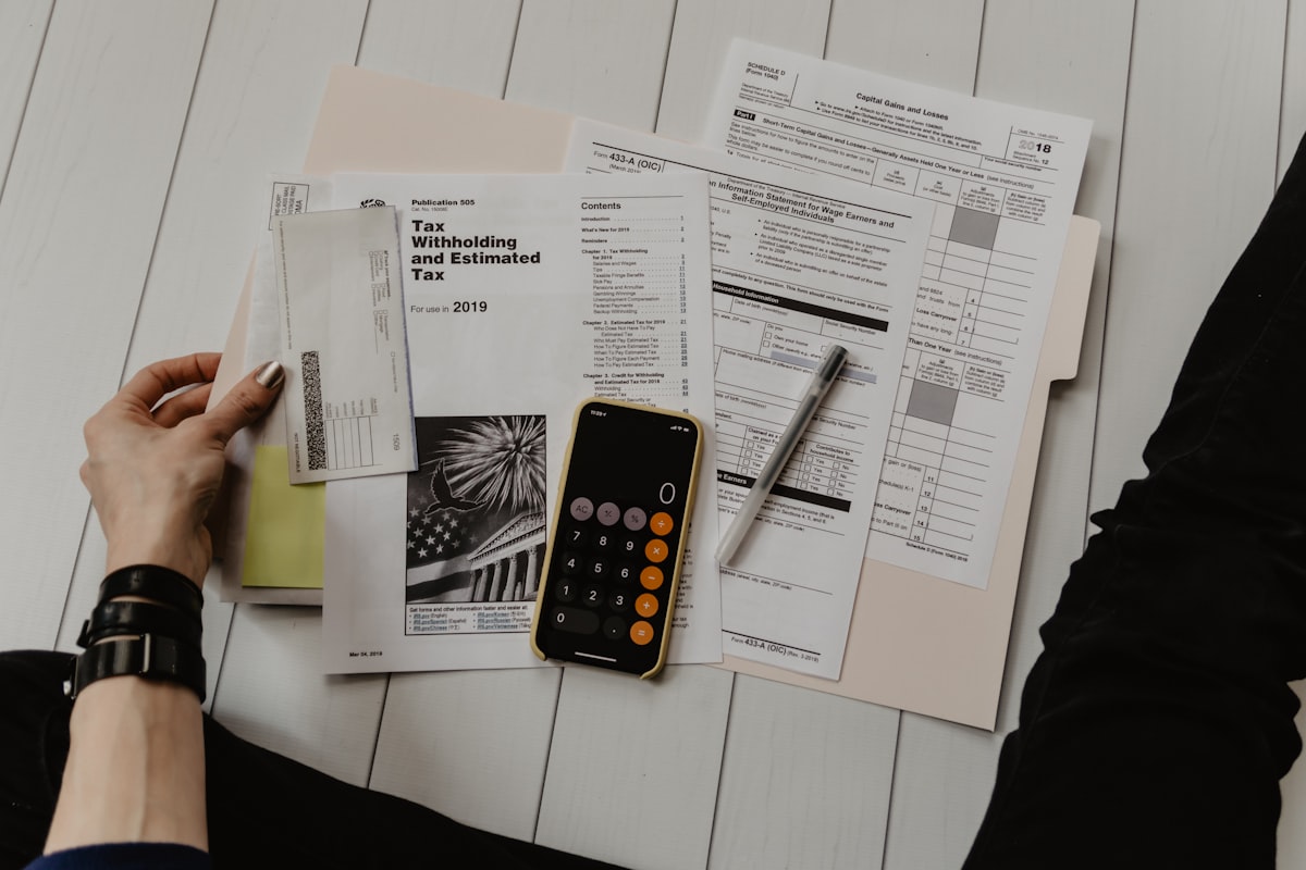 Financial planning workspace with calculator and documents representing bail monitoring program budget and GPS ankle bracelet total cost of ownership